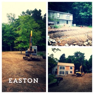 Excavator on lawn in easton connecticut and in front of new construction