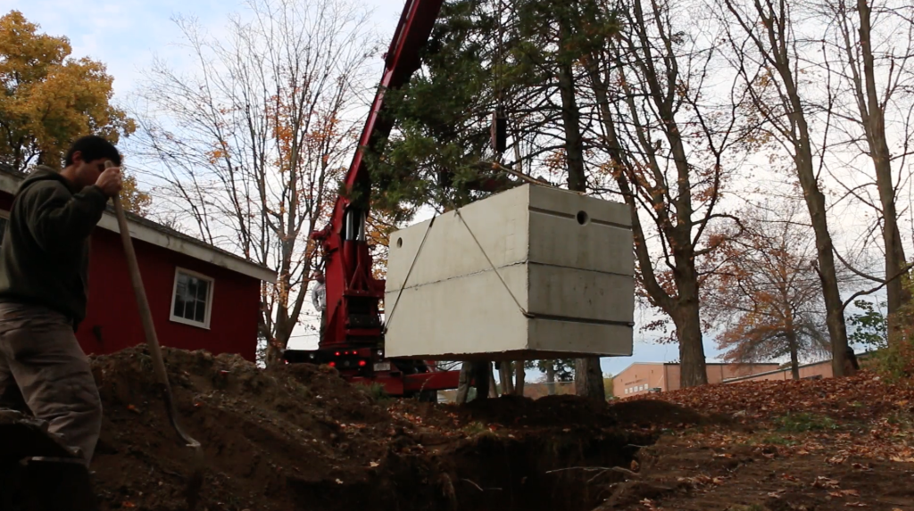crane truck lowers concrete septic tank