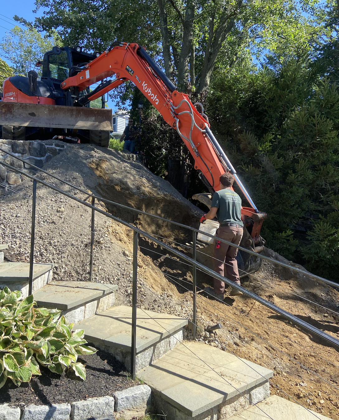 Excavator building a dirt ramp down a slope to install a septic tank